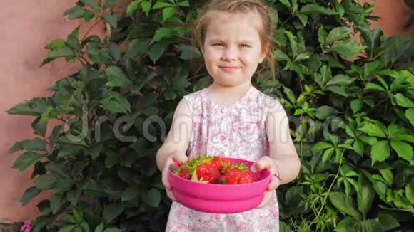 小可爱的漂亮女孩伸出手拿着草莓浆果视频的预览图