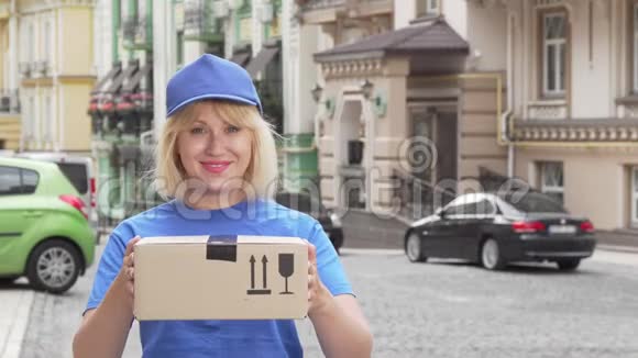 穿着蓝色制服拿着纸箱的快乐的送货员视频的预览图