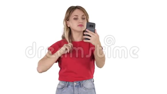 一个漂亮的年轻女人在白色的背景上看着手机直着她的头发视频的预览图