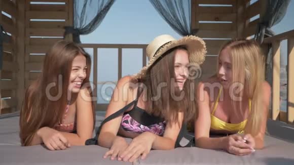 快乐的女性朋友快乐地在阳光明媚的夏日在豪华度假胜地的平房里欢乐地度过时光视频的预览图
