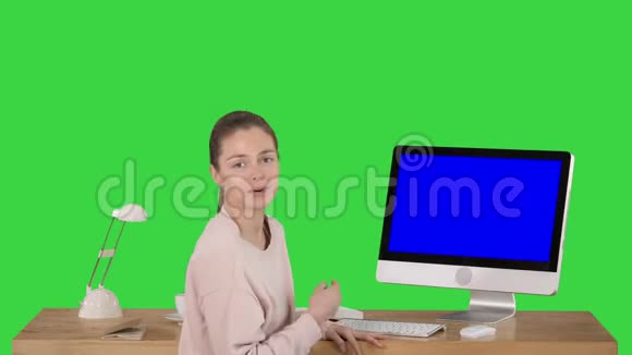 一位迷人的女士在电脑屏幕上展示了一些东西她正在和摄像机交谈屏幕上是一个绿色的蓝屏模拟显示屏视频的预览图