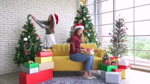 亚洲妇女装饰圣诞树为12月的圣诞节准备礼物视频的预览图