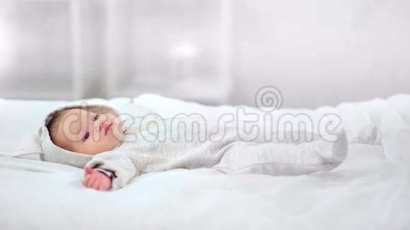 柔软的妈妈手牵着可爱的小宝宝在床上醒来在白色的室内享受早晨视频的预览图