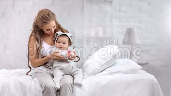 家庭幸福的女人和可爱的婴儿快乐的早晨在白色房间的内部背景下玩耍视频的预览图