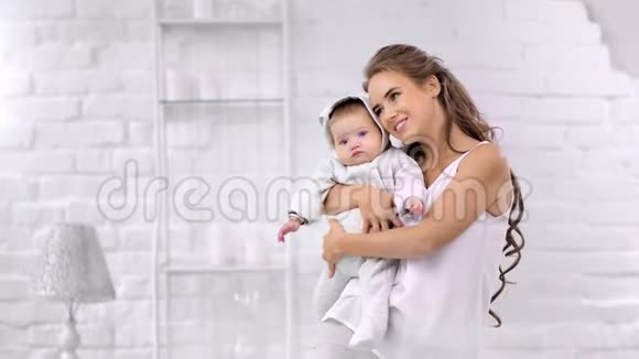快乐美丽的母亲拥抱小婴儿有最好的感觉享受早晨的白色房间视频的预览图