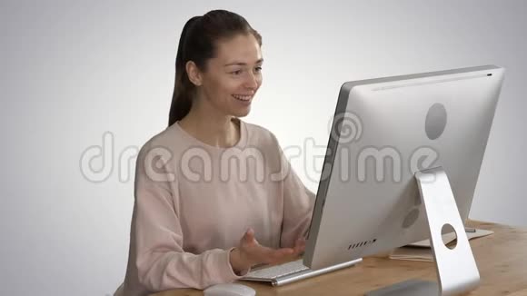 快乐的女人坐在她的电脑前的梯度背景视频电话视频的预览图