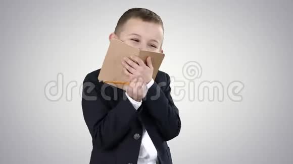 情绪积极的小男孩与笔记本笑在梯度背景视频的预览图