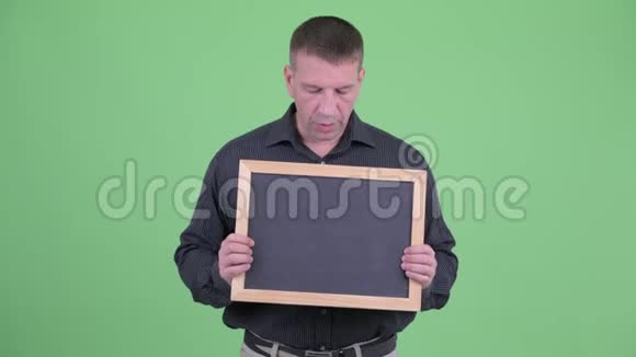 马奇成熟的商人一边拿黑板一边说话视频的预览图