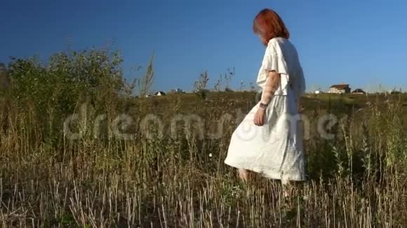 年轻女子走过绿色的田野视频的预览图