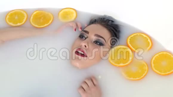 性感的年轻女孩摆姿势躺在浴室里放着牛奶和鲜橙片视频的预览图