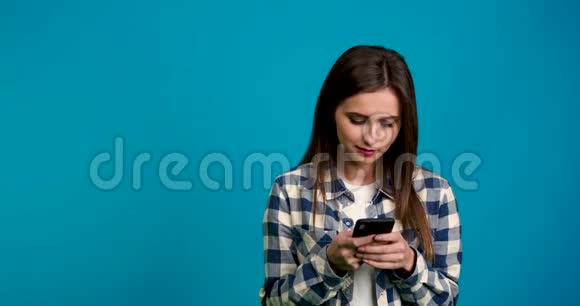 女孩微笑着向外看并在智能手机上打字视频的预览图