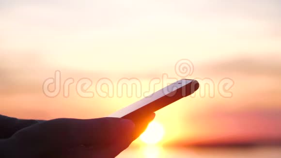 年轻女子在日落时分使用智能手机视频的预览图
