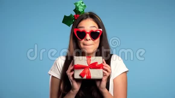 漂亮的年轻女孩微笑后收到礼品盒蓝色工作室背景视频的预览图