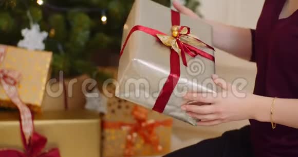 妇女手持礼品盒在圣诞树下放置视频的预览图