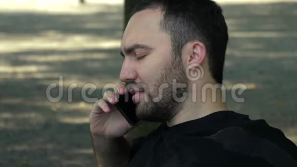 英俊的年轻人在公园里打电话视频的预览图