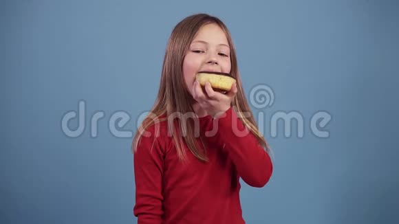 穿红色毛衣的小女孩正在彩色背景上吃巧克力甜甜圈享受这种味道7岁至10岁儿童视频的预览图