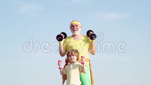 活跃的家庭享受运动和健身有趣的老人和带哑铃的小孩爷爷和孩子早上视频的预览图