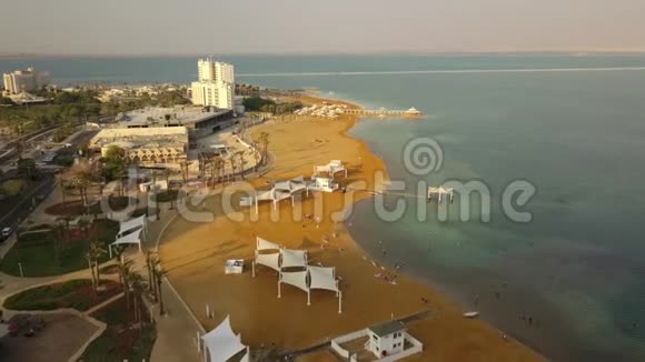 一只鸟在死海海滩上飞行的全景酒店和平静的碧水视频的预览图