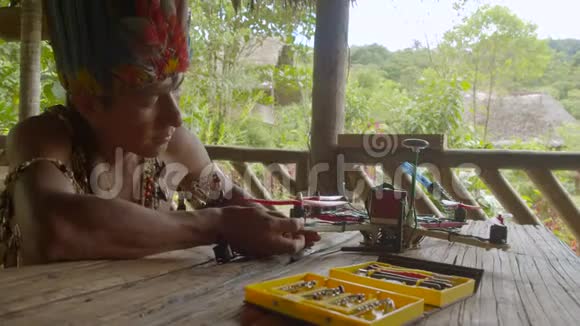 一位年轻的土著人在他的乡村小屋里建造了一架diy无人机视频的预览图