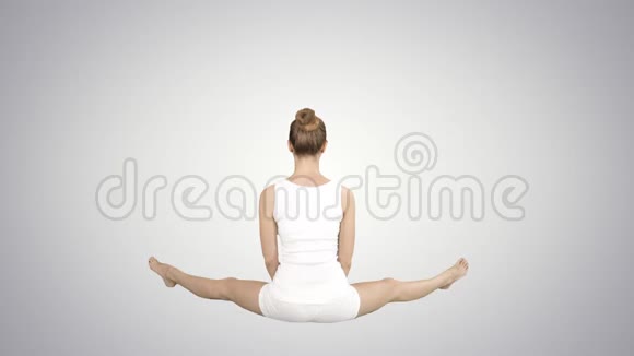 美丽的年轻女子穿着运动服坐在渐变背景上的莲花姿势练习瑜伽视频的预览图