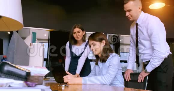 办公室里的三个同事看着笔记本电脑屏幕视频的预览图