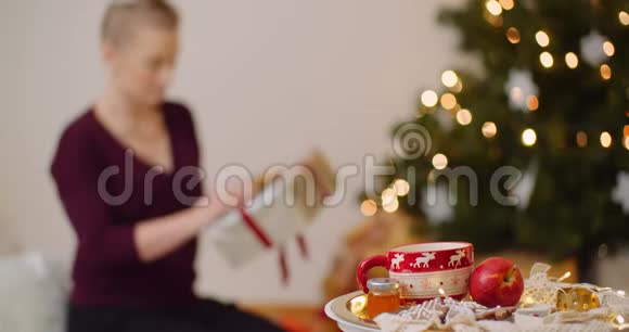 妇女手持礼品盒在圣诞树下放置视频的预览图