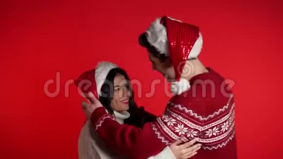 戴圣诞圣诞圣诞老人帽子亲吻和拥抱的年轻夫妇的肖像视频的预览图