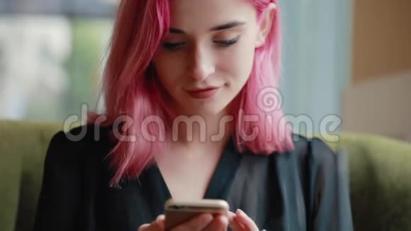 咖啡馆里一个使用智能手机的粉红头发女人视频的预览图