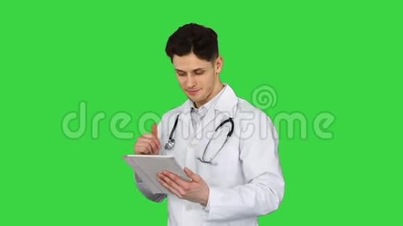 漂亮自信的医生在绿色屏幕上阅读结果后用平板电脑跳舞色度键视频的预览图
