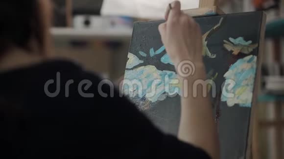 女人正在用油画颜料在画布上画一幅画透过肩膀看视频的预览图