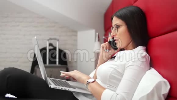 忙碌的女商人用智能手机聊天讨论工作看笔记本电脑屏幕视频的预览图