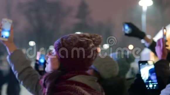圣诞音乐会上的人群在舞台附近举起双手在智能手机摄像头上录制视频和自拍照片视频的预览图