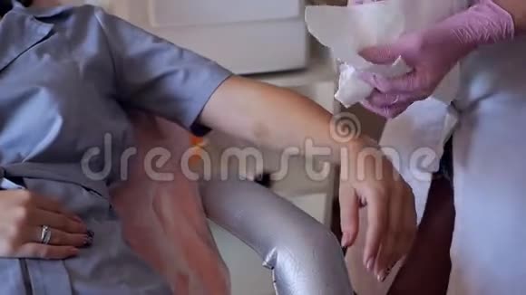 激光脱毛美容院的激光脱毛女美容师用一个特殊的档案擦拭手后视频的预览图