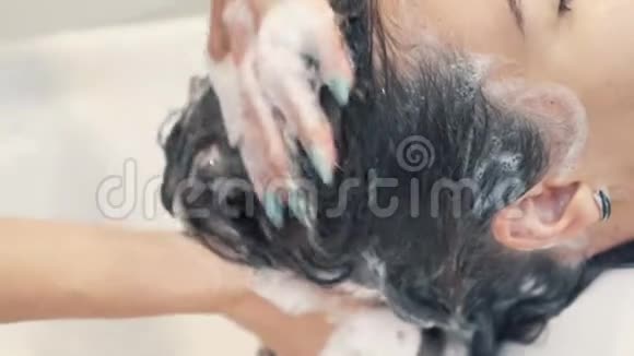 将理发师用洗发精的手收起来给女人洗头动作缓慢视频的预览图
