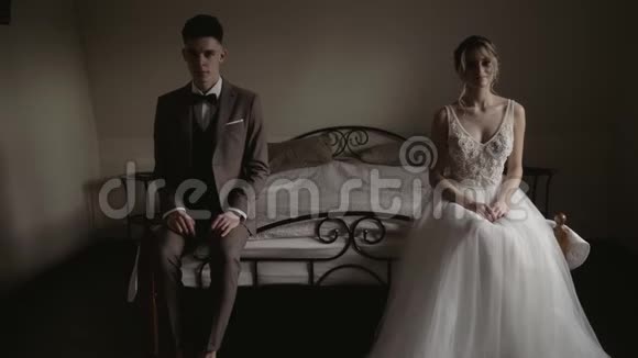 年轻漂亮的情侣穿着婚纱坐在床上新婚夫妇坐在床上视频的预览图