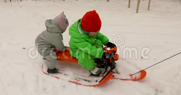 穿着冬装的可爱的孩子们一起坐着雪橇视频的预览图