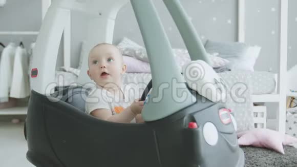 快乐的宝宝在家坐在玩具车里抬头视频的预览图