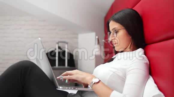 一位精力充沛精力充沛的年轻女商人在酒店阁楼的床上工作手提电脑视频的预览图