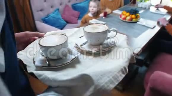 一家人坐在旅馆的餐馆里一个侍者把咖啡带到桌子上视频的预览图