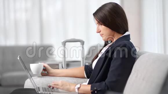 商务旅行时女商务人士在笔记本电脑上喝茶打字中等特写视频的预览图