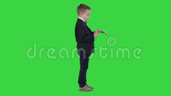 穿黑色西装的小男孩在绿色屏幕上数数钱Chroma键视频的预览图