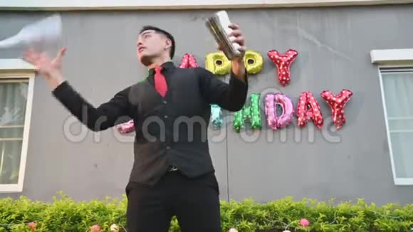 漂亮的亚洲男调酒师穿着黑色正式西装戴着红色领带扔瓶子做兼职工作视频的预览图