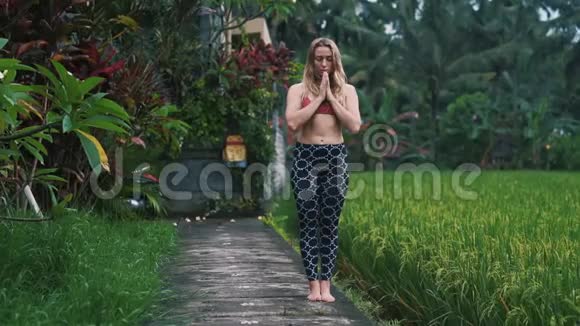 年轻女性在户外做瑜伽运动和伸展运动背景是绿色植物视频的预览图
