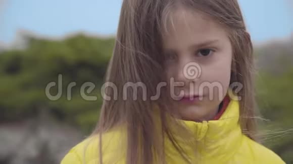 一个棕色眼睛穿着黄色外套的漂亮白人女孩的特写肖像可爱的孩子站在秋天视频的预览图