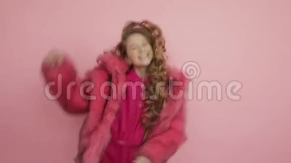 一个美丽的年轻女孩一头金发正在粉色背景上跳舞视频的预览图