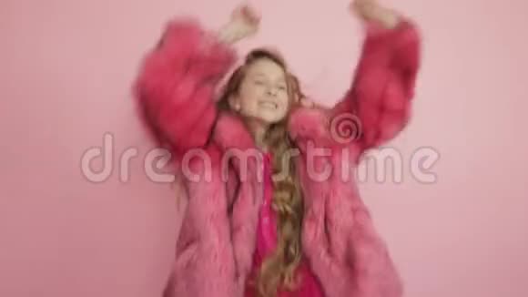 美丽的年轻女孩红色卷发在粉红色的背景上跳跃和跳舞视频的预览图