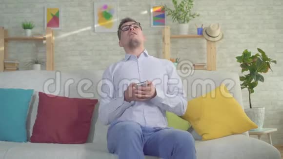 一名携带智能手机的男子在家中的沙发上癫痫发作视频的预览图