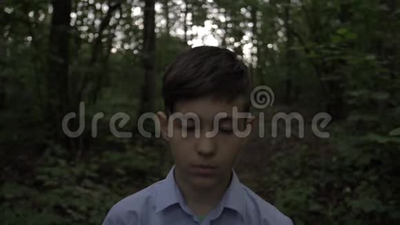 傍晚森林慢动作中悲伤男孩的肖像视频的预览图