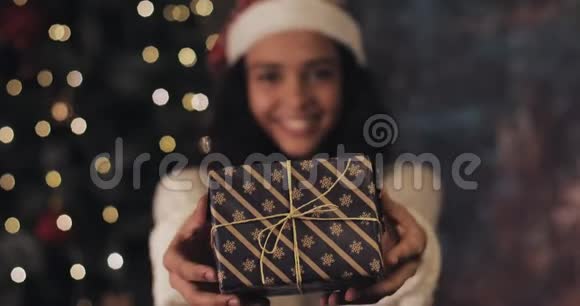 合上圣诞老人帽子里漂亮的笑脸女孩并把圣诞礼物盒收回照相机站着视频的预览图