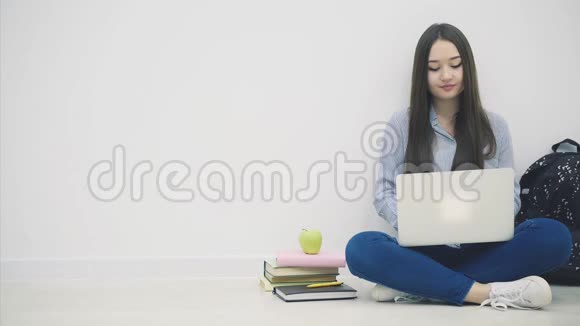 疲惫的年轻亚洲女士坐在地板上坐在洛托斯的位置上拿着笔记本电脑打哈欠休息一下吃苹果视频的预览图